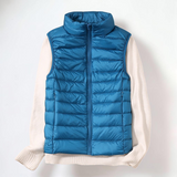 Colete acolchoado azul Elara München sobre camisola de malha bege, ideal para sobreposição leve e quente.